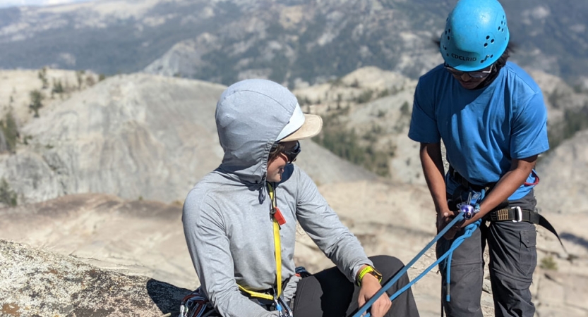 an instructor gives direction to a student preparing to rock climb on an outward bound trip